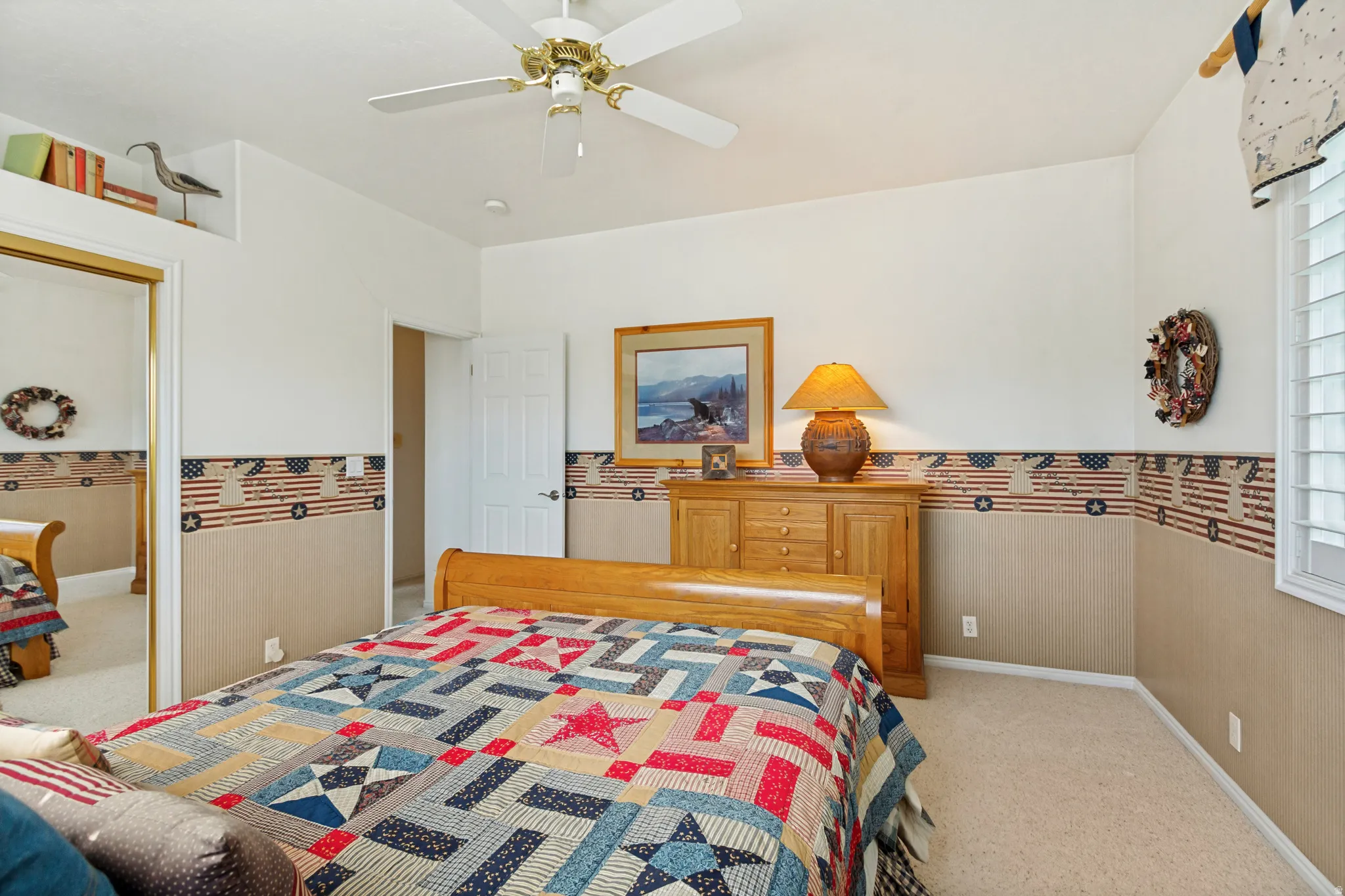 Carpeted bedroom featuring a light-colored wooden bed frame, a matching wooden dresser, and a window with white louvered shutters