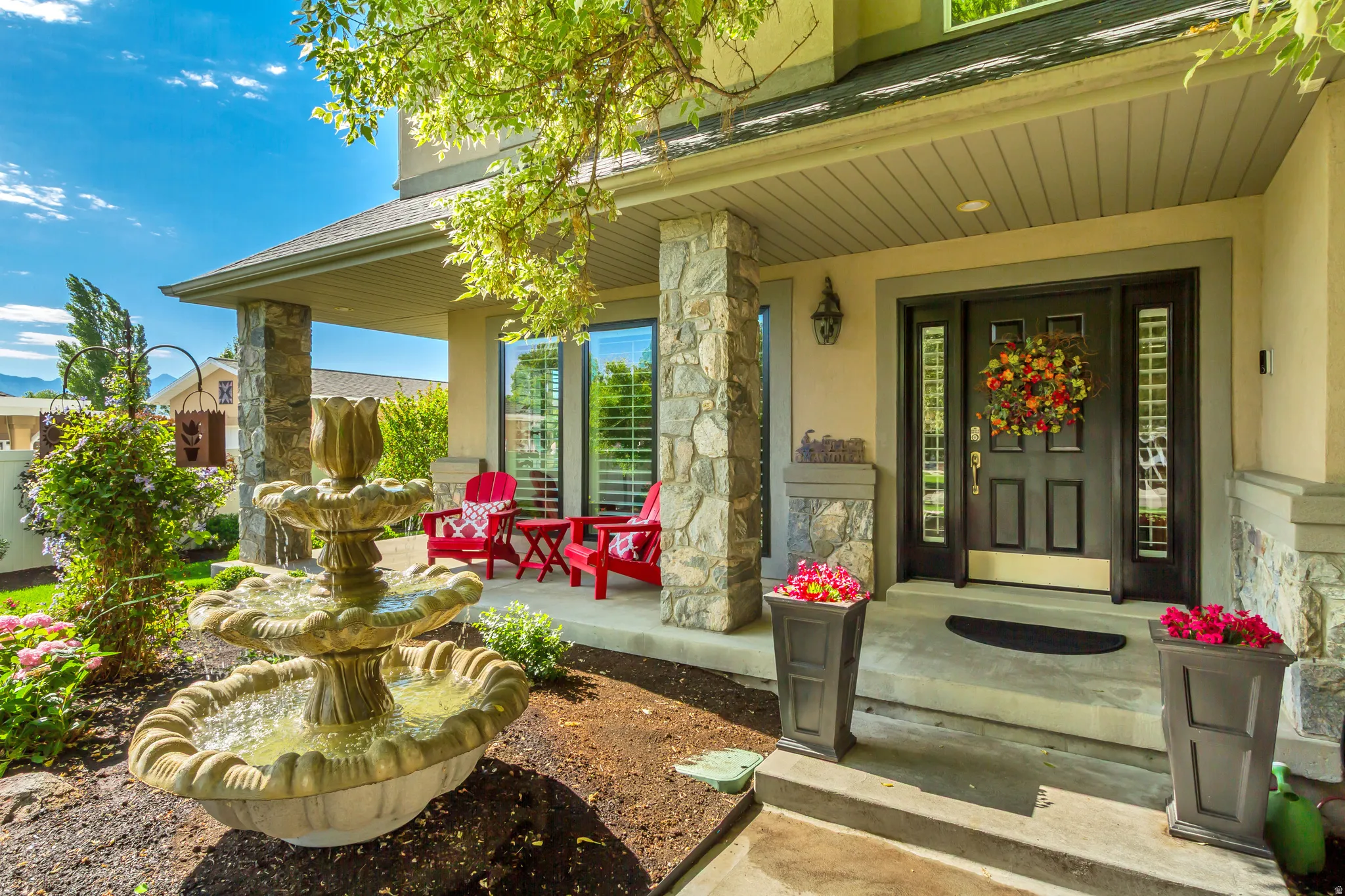 Stone-clad columns define the covered porch entry, featuring a dark wood-finish door with sidelight windows