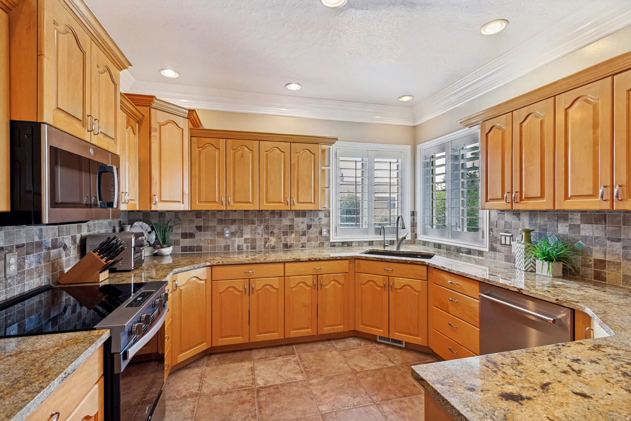 Kitchen featuring wood cabinetry, granite countertops, a stainless steel microwave, and a stainless steel dishwasher
