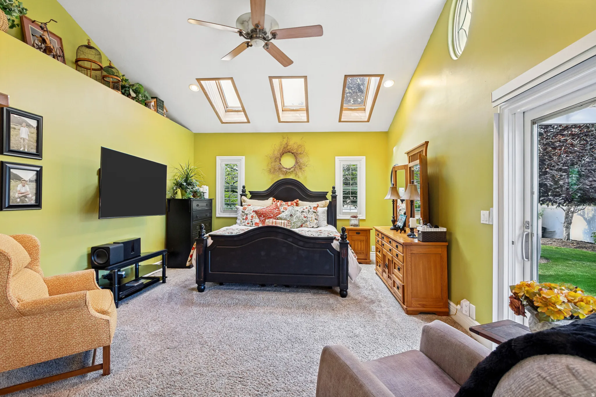 Carpeted interior space featuring a vaulted ceiling with skylights, ceiling fan, and a built-in display ledge