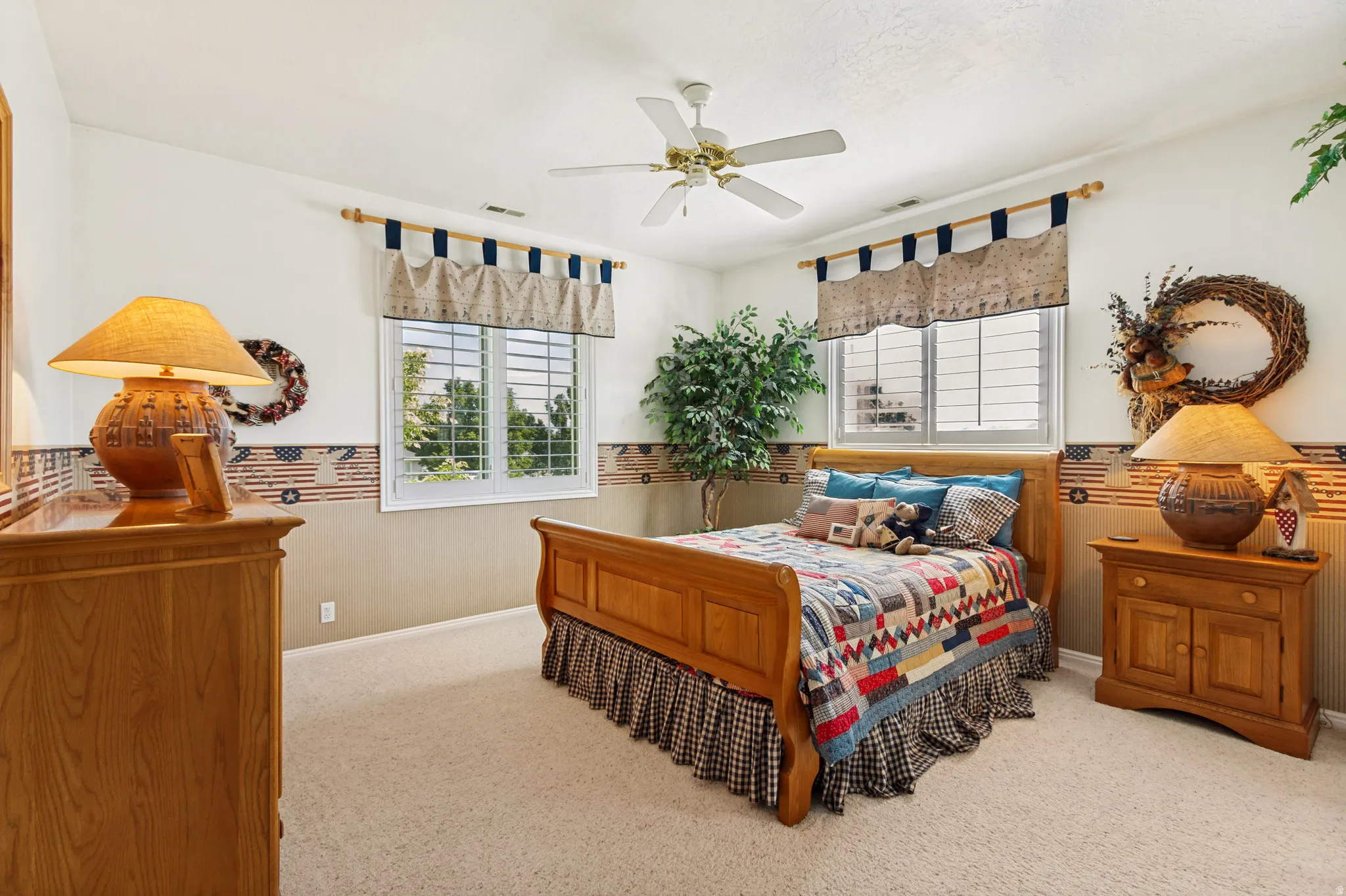 Carpeted room featuring a ceiling fan, two windows with blinds, and white trim