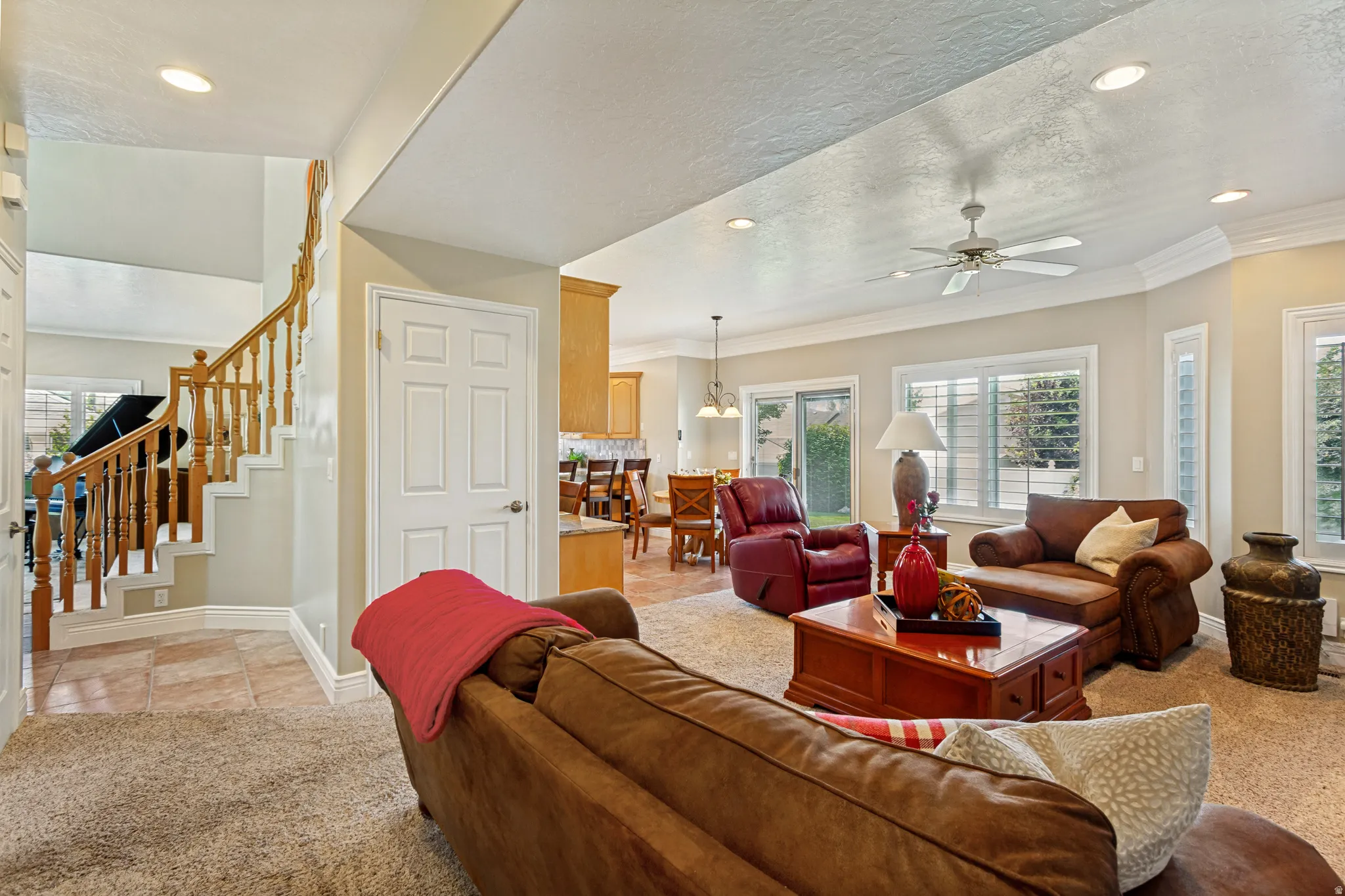 Spacious living area featuring neutral carpeting, recessed lighting, and a ceiling fan