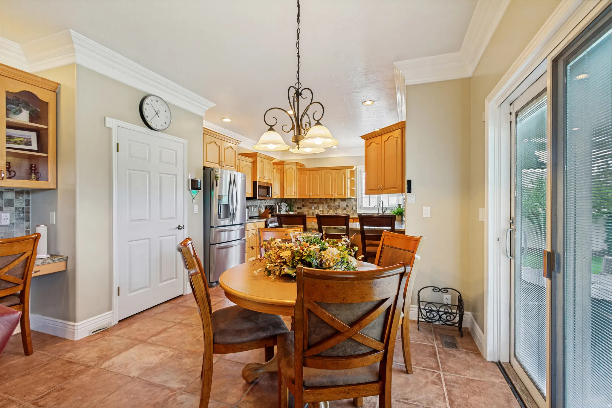 Dining area featuring natural wood cabinetry, a tile backsplash, stainless steel appliances, and tile flooring