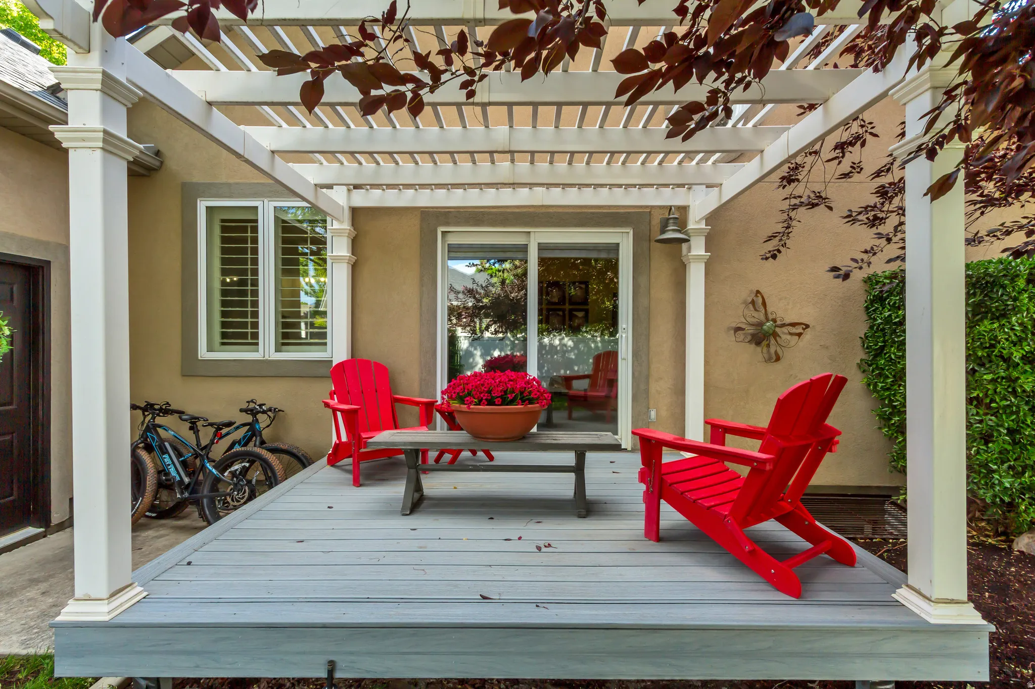 Expansive outdoor deck featuring a white pergola structure and a sliding glass door