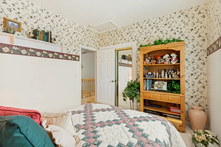 Room featuring floral wallpaper, white trim, and a built-in shelving unit