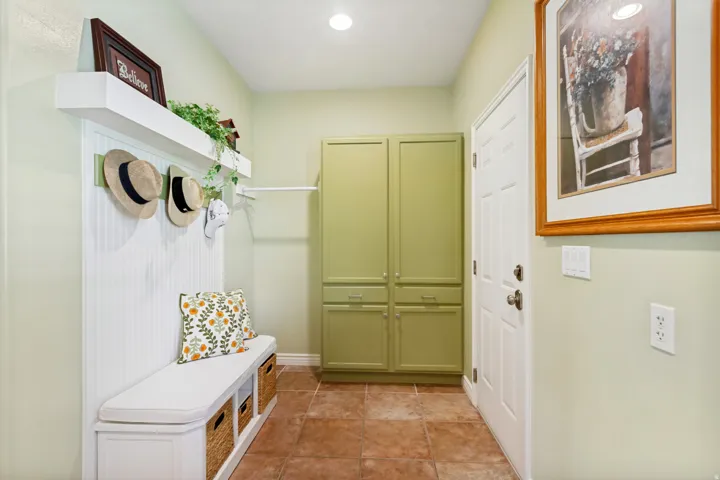 Entryway featuring an integrated bench with storage, beadboard paneling, and an overhead shelf