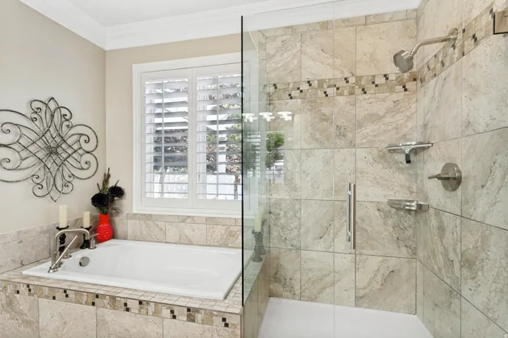 Built-in soaking tub with brushed nickel fixtures and surrounding tilework