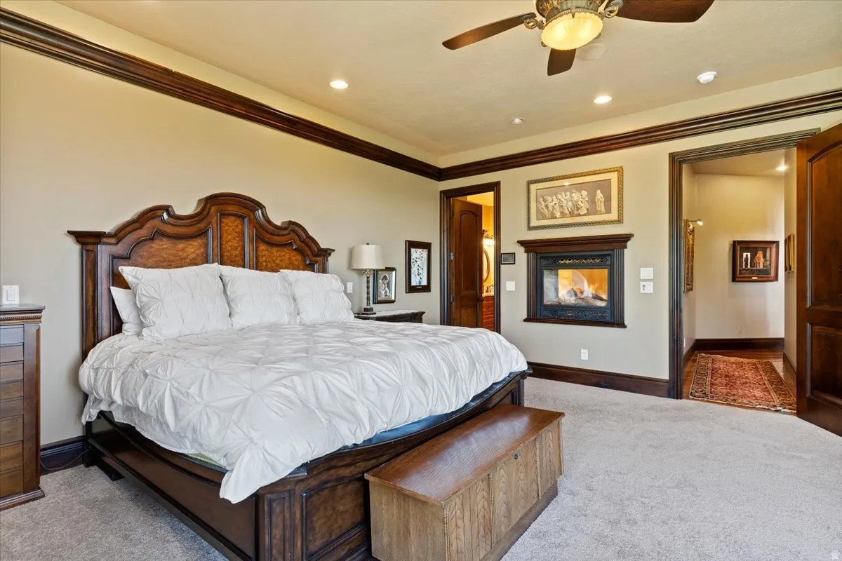 Bedroom featuring recessed lighting, a ceiling fan, crown molding, a built-in fireplace with a dark wood surround, and dark wood trim