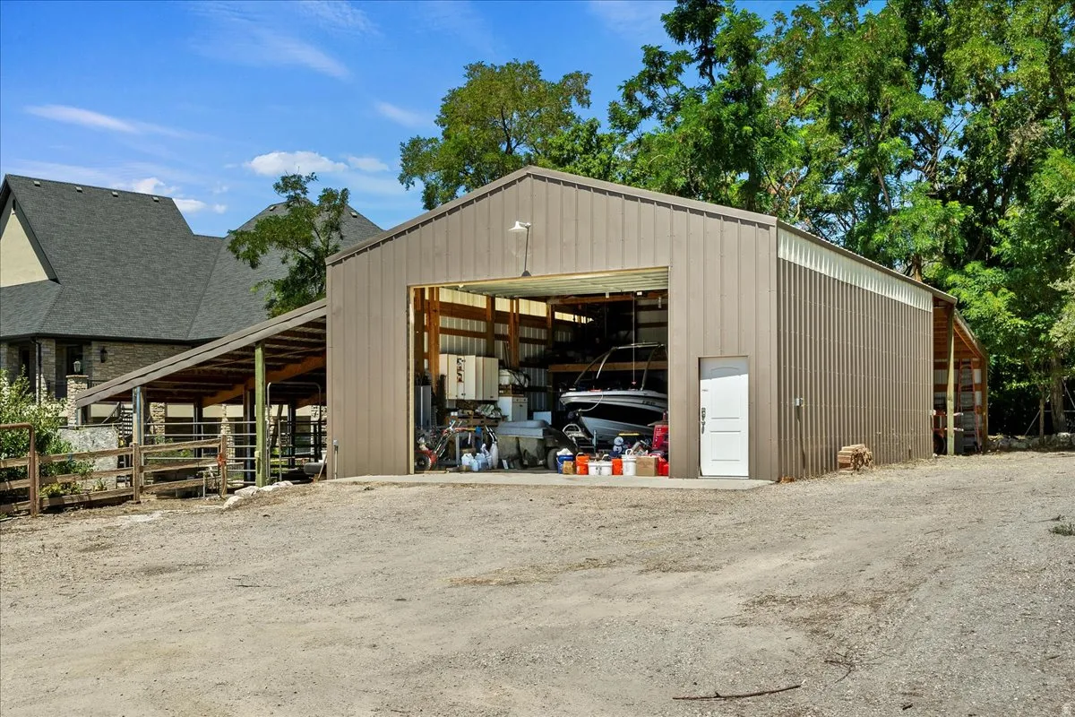 Metal-sided barn structure featuring an open bay and an additional side entrance