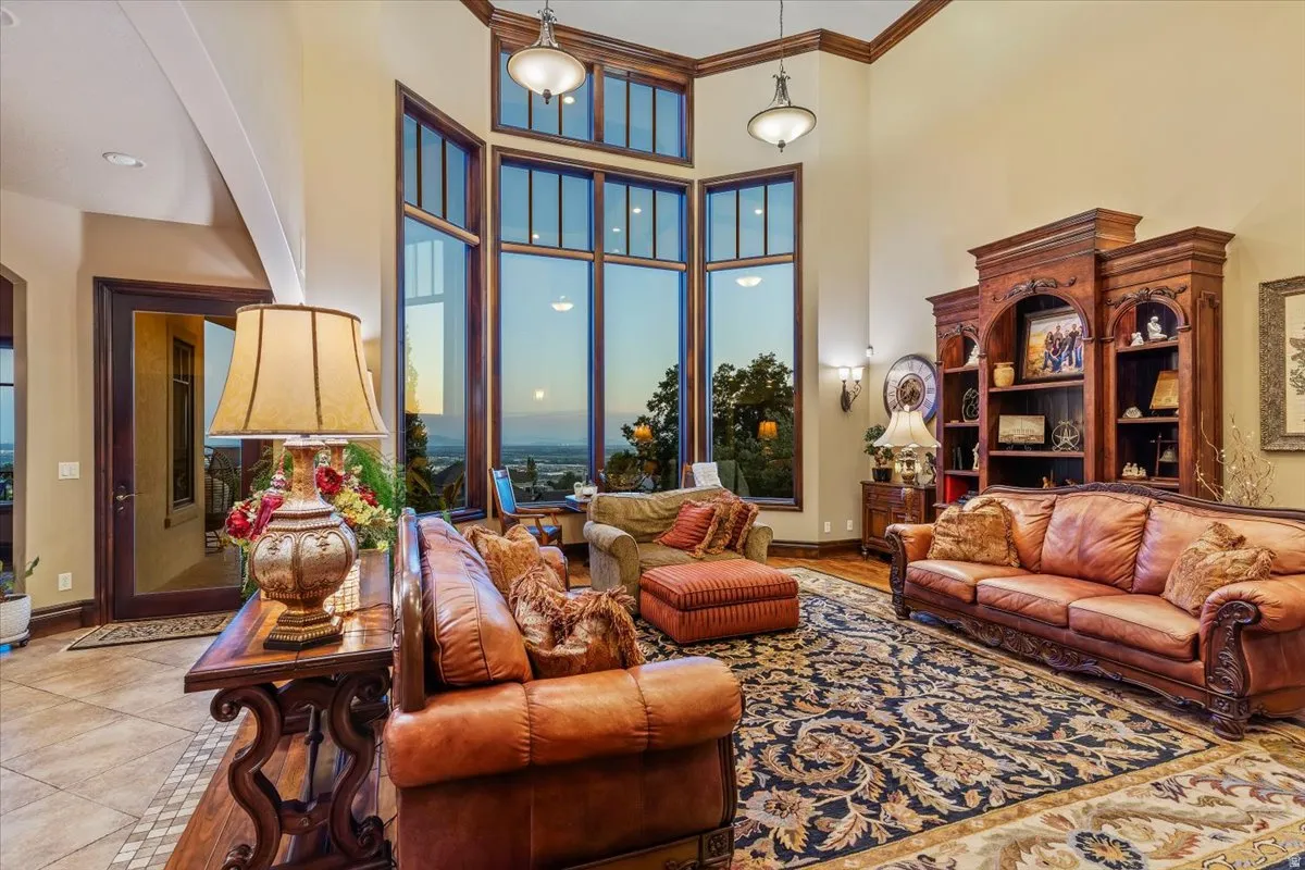 Two-story living area featuring extensive window walls, detailed wood trim, high ceilings, a decorative area rug, and built-in cabinetry