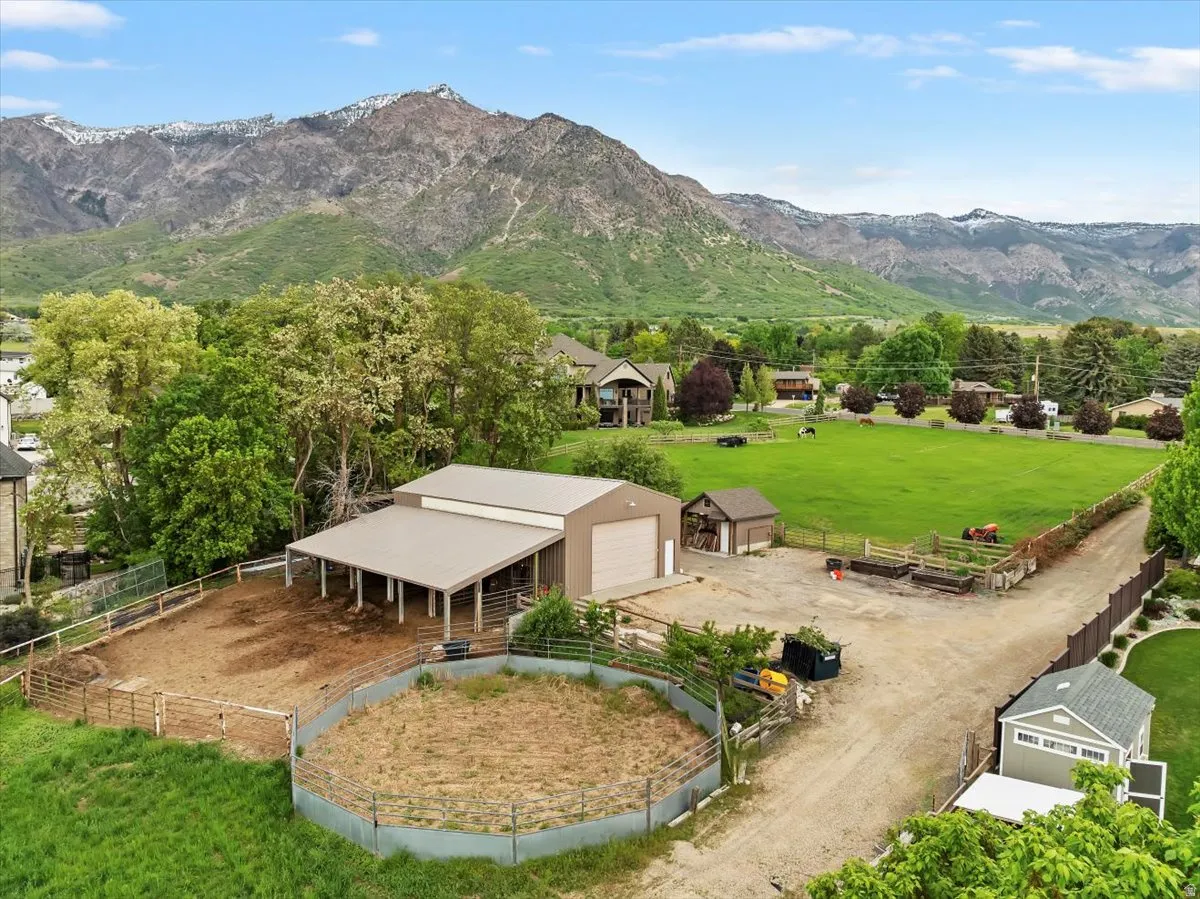 Expansive property featuring a large barn with covered stalls and two garage doors, a fenced riding pen, and a secondary outbuilding