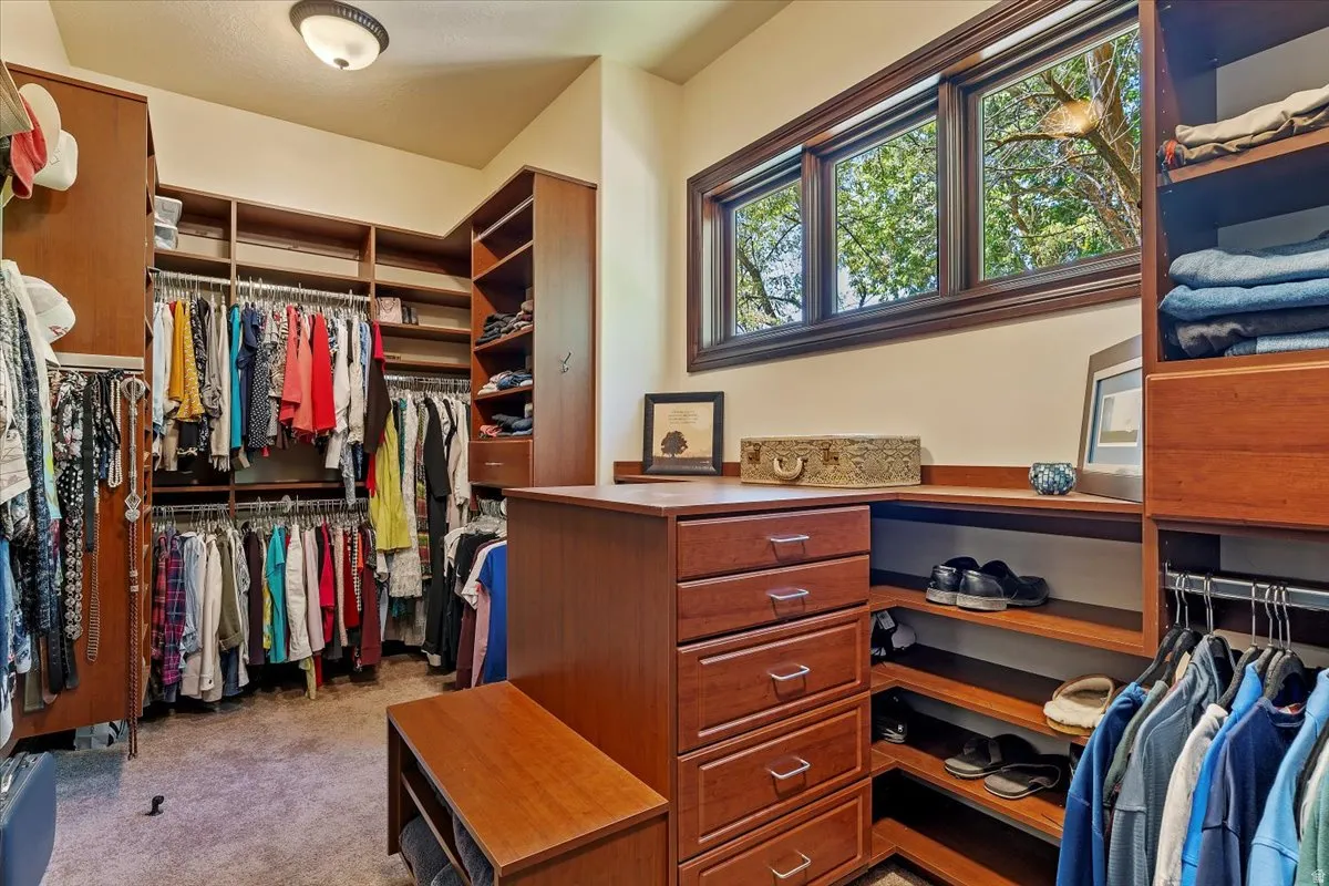 Custom built-in closet system featuring warm wood-finish cabinetry, ample shelving, and multiple hanging rods