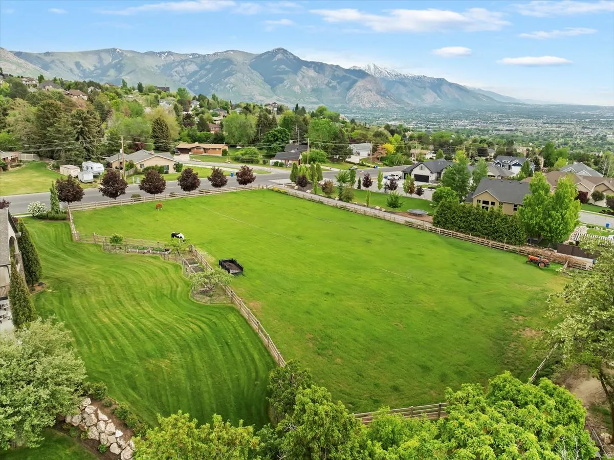 Expansive green lot featuring manicured lawns, a fenced perimeter, and established landscaping