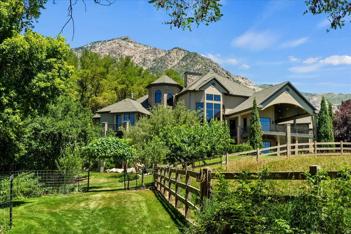 Lower Orchard, featuring fruit trees & bushes. Mountain backdrop with a multi-level residence featuring a stone-clad turret and expansive windows