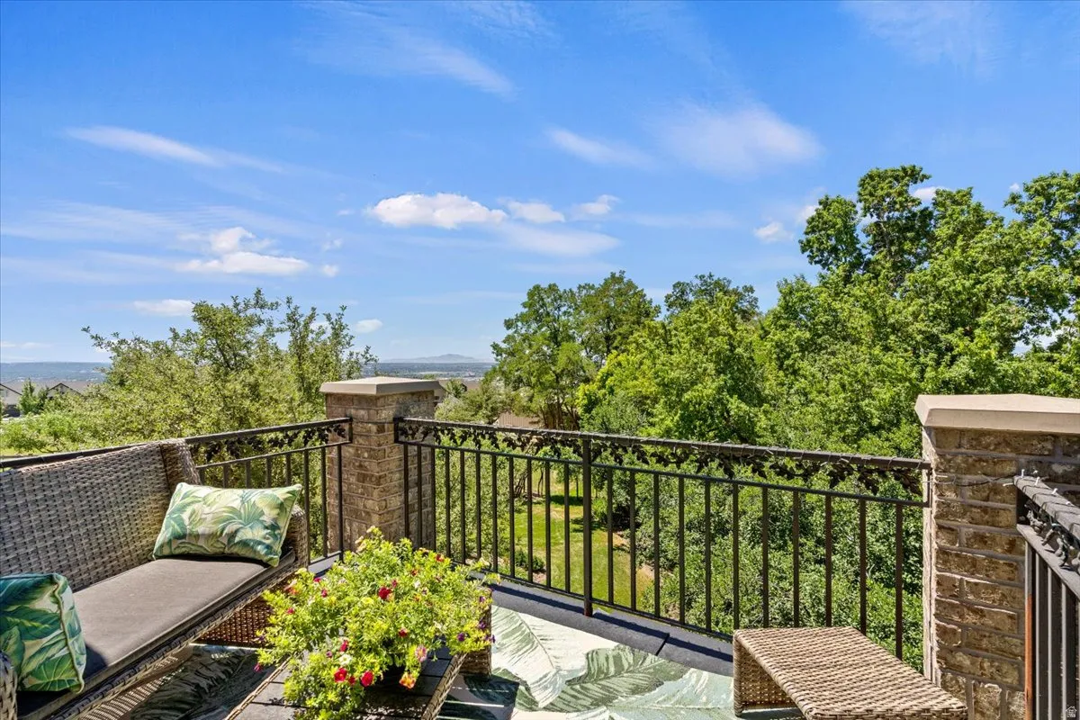 Elevated outdoor patio featuring brick masonry columns with stone caps, decorative wrought iron railing, and a clear sky overhead