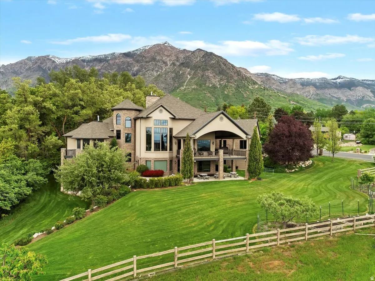 Two-story residence featuring a combination of stone and stucco siding, a multi-level deck, and an expansive lawn