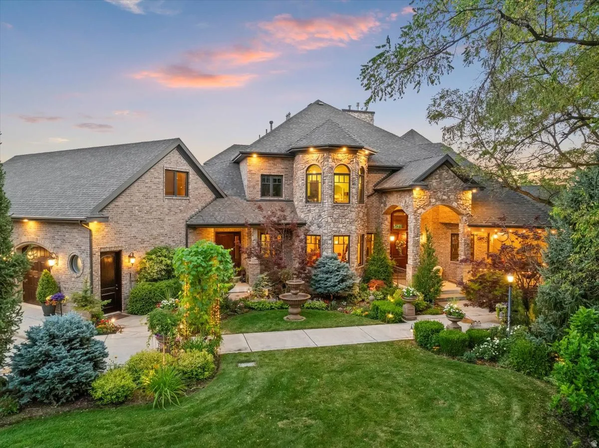 Stately brick and stone exterior with architectural turrets, custom lighting inside and out, and meticulous landscaping.