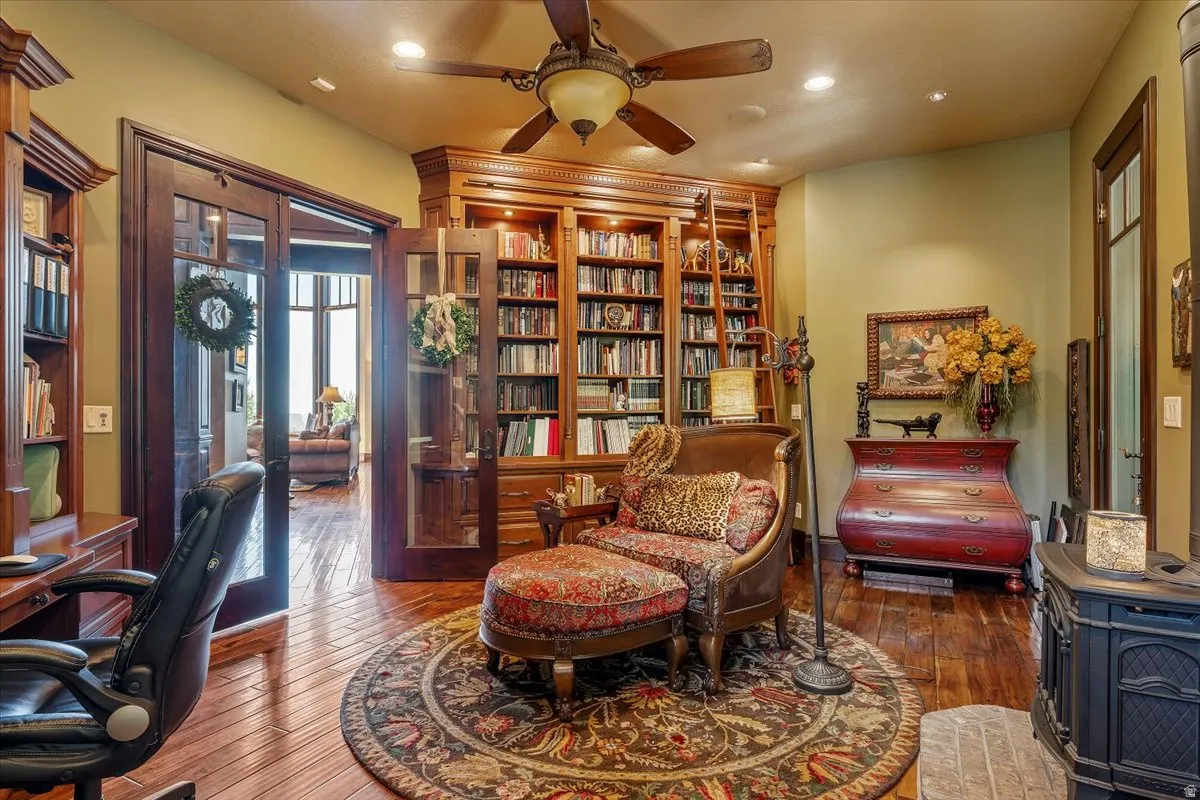 Expansive built-in shelving with rolling ladder, wood-finish flooring, recessed lighting, and a ceiling fan