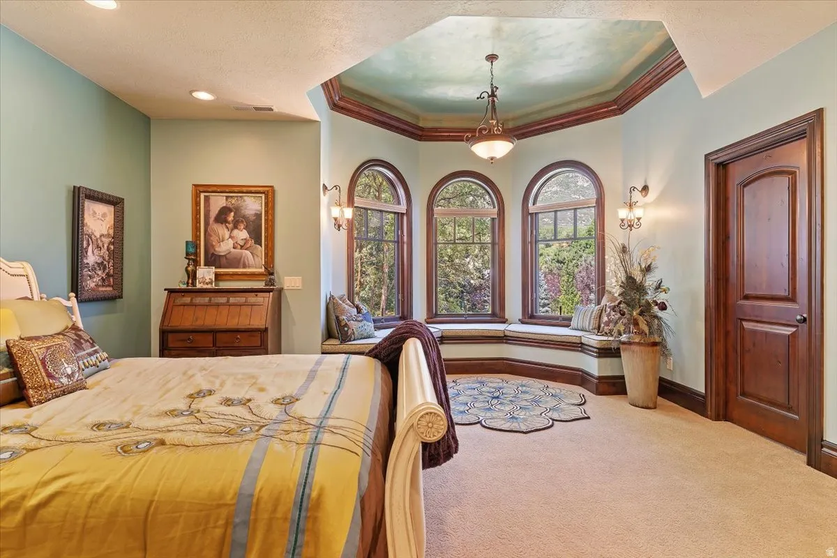 Windowed alcove featuring three arch-top windows with built-in window seating, complemented by a tray ceiling with a central chandelier