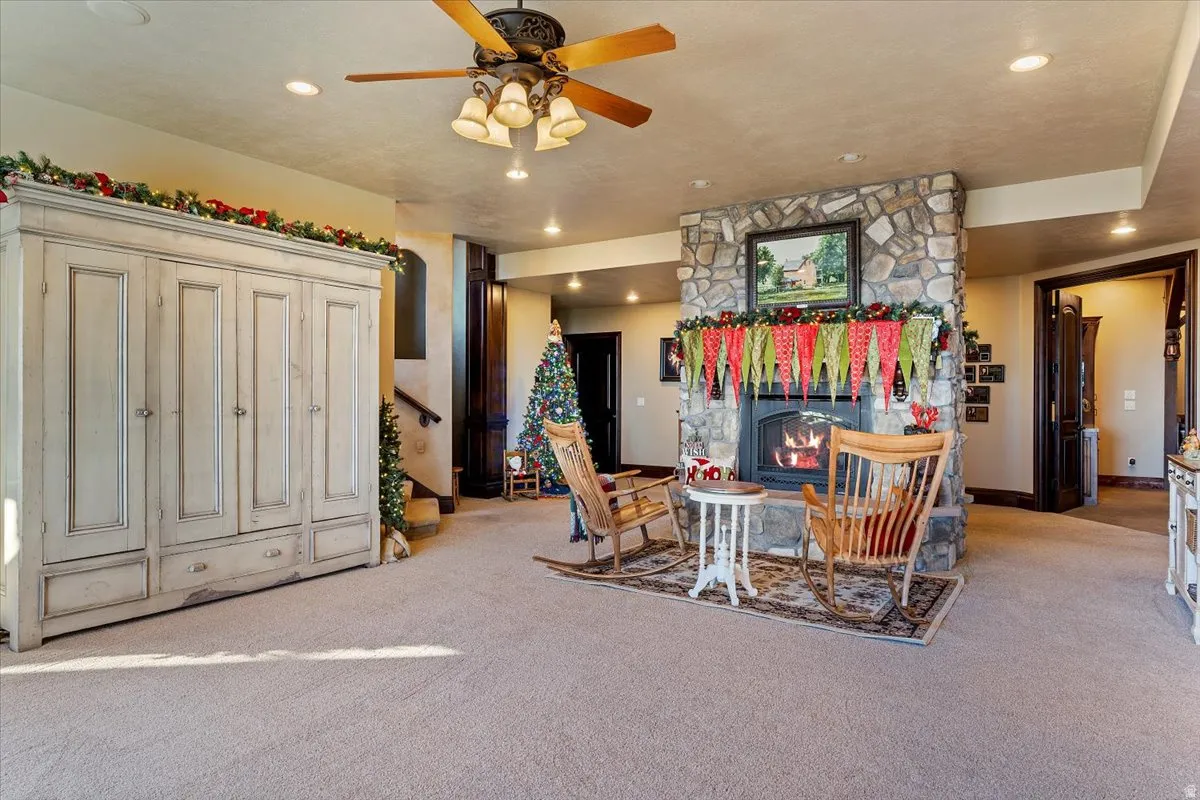 Stone-clad fireplace with a raised hearth, recessed lighting, and a ceiling fan with integrated lighting