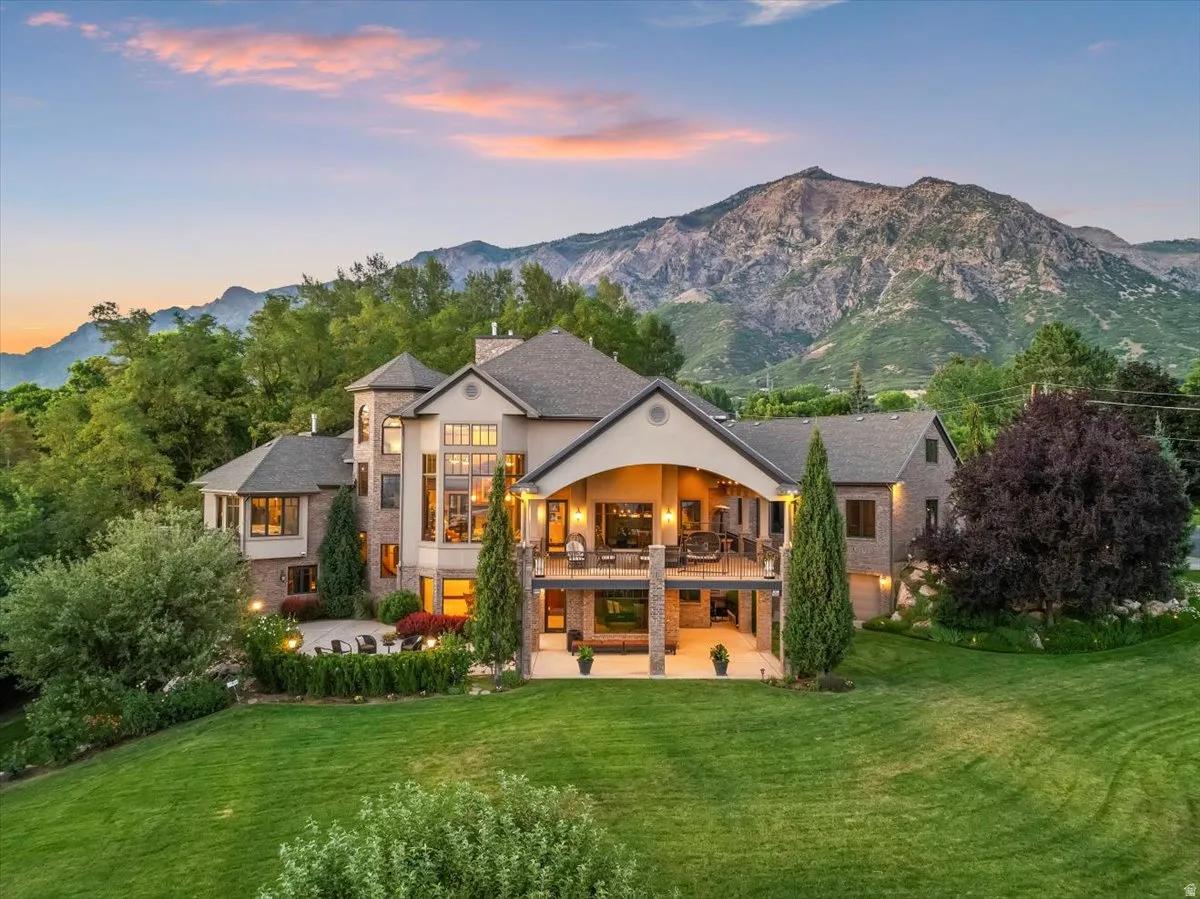 Expansive property featuring a multi-level residence with a brick and stone facade, a covered upper-level patio, and a lower-level patio