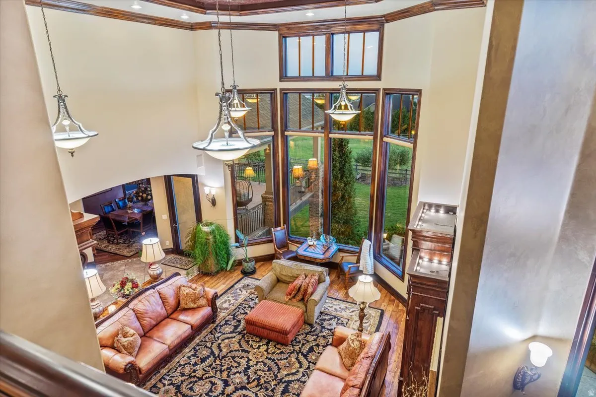 Two-story living area featuring a vaulted ceiling with exposed wood beams, hardwood flooring, and multiple pendant light fixtures