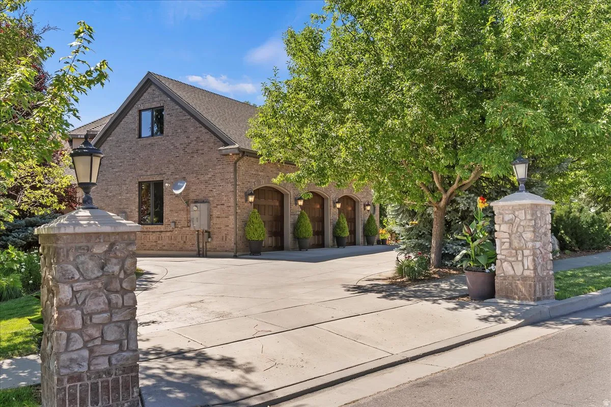 Stone pillars with integrated lanterns frame the concrete driveway