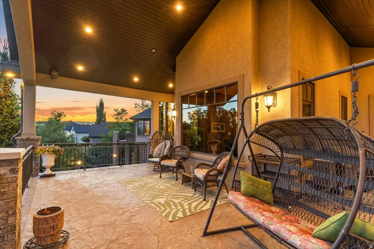 Spacious covered patio featuring a concrete surface, recessed lighting, brick accent pillars, and a decorative metal railing. Unmatched views