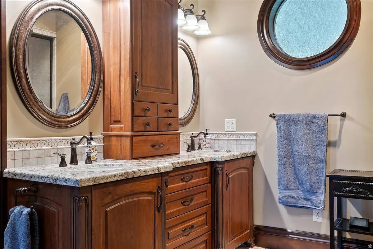 Dual vanity with wood-finish cabinetry, stone countertops, and bronze-finish fixtures