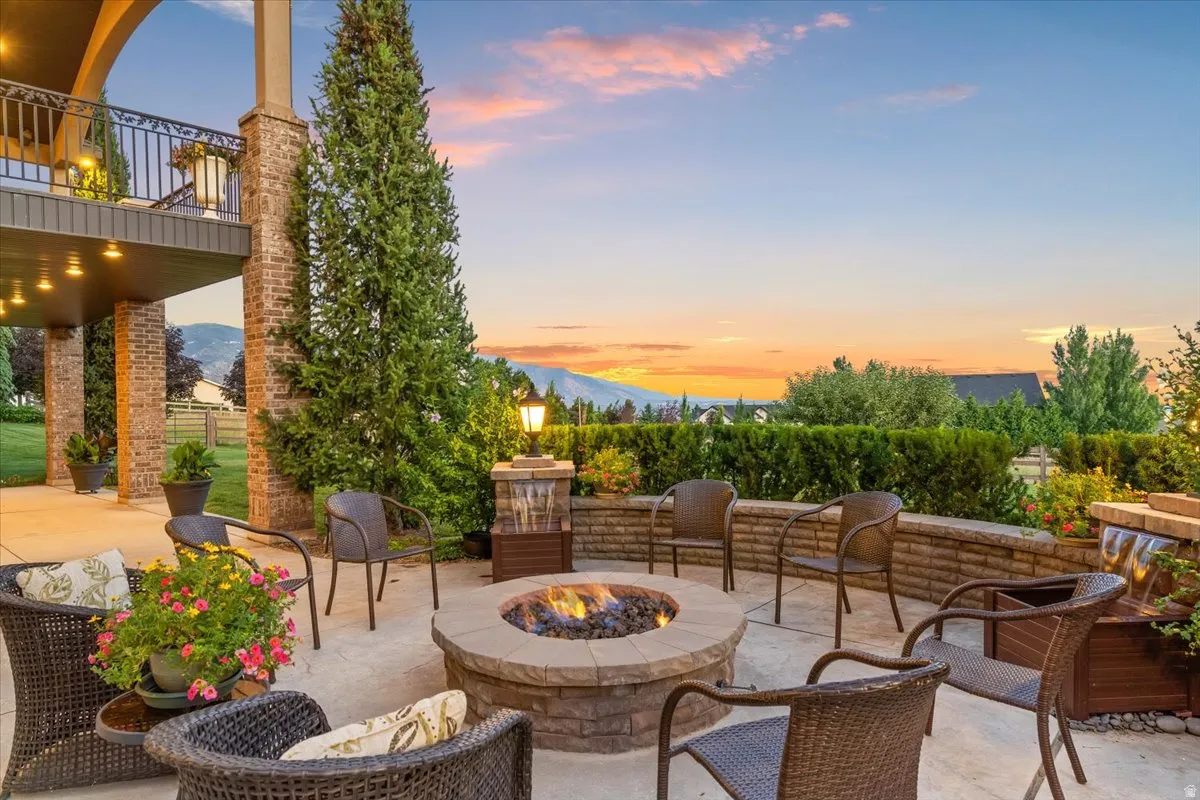 Expansive outdoor living area featuring a built-in stone fire pit, concrete patio, and a tiered retaining wall