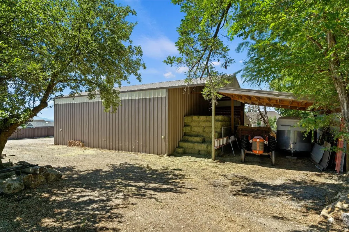 Metal barn structure featuring a corrugated roof, light brown siding, and an attached covered lean-to