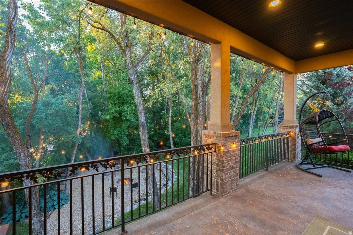 Covered outdoor patio featuring recessed lighting, string lights, and a decorative wrought iron railing with brick pillars