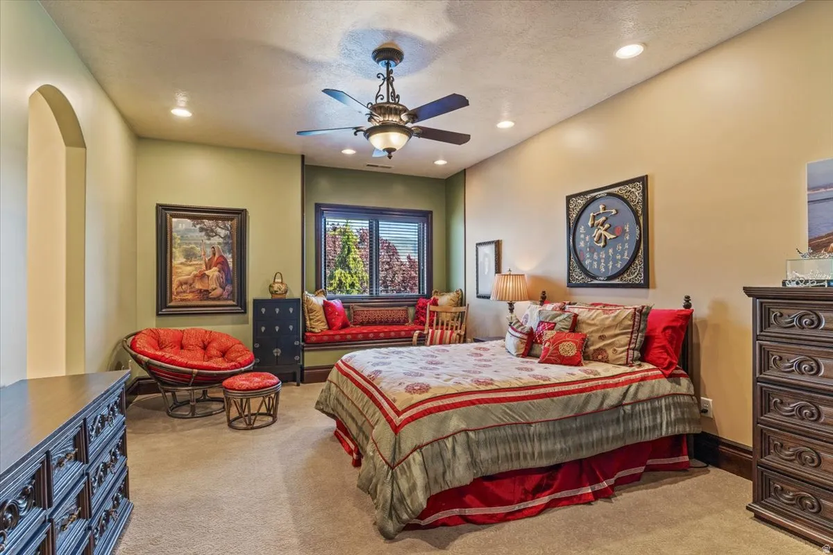 Spacious room featuring a large window with horizontal blinds, recessed lighting, a ceiling fan with integrated lighting, and neutral-toned carpeting