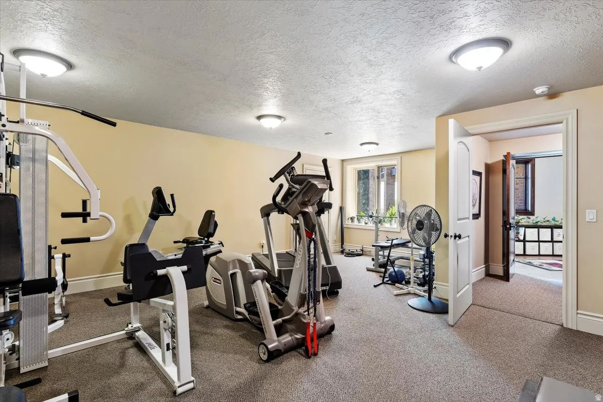 Large dedicated fitness space featuring neutral wall tones and recessed lighting