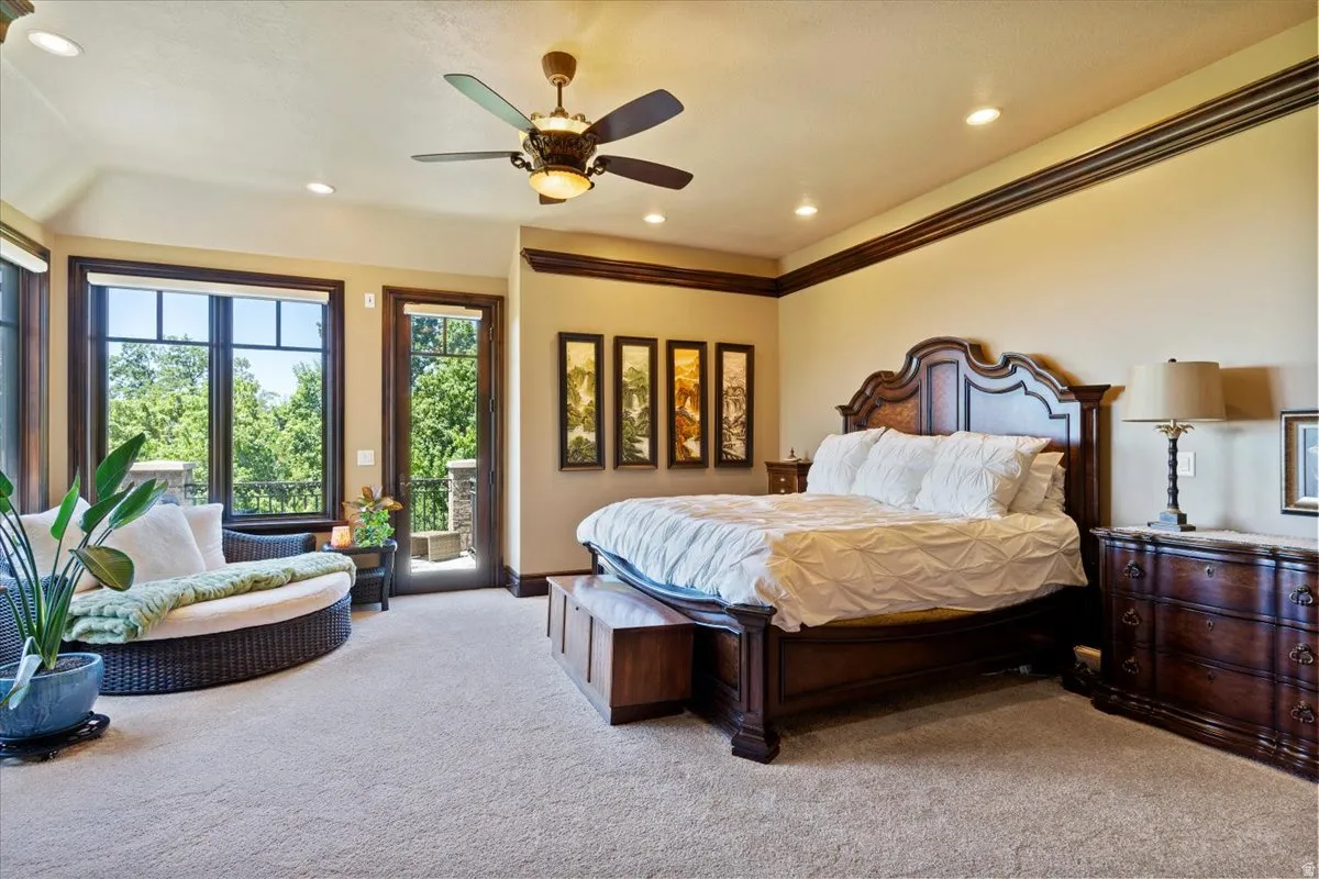 Spacious bedroom featuring warm neutral walls, dark wood trim, recessed lighting, and a ceiling fan