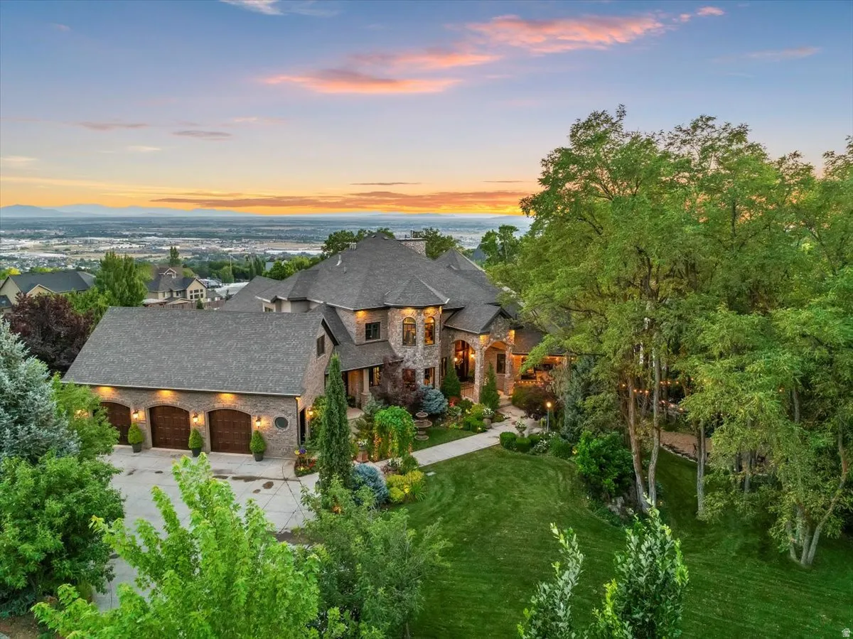 Expansive property featuring a stone and brick exterior, a multi-car garage with arched wooden doors, and a terraced lawn