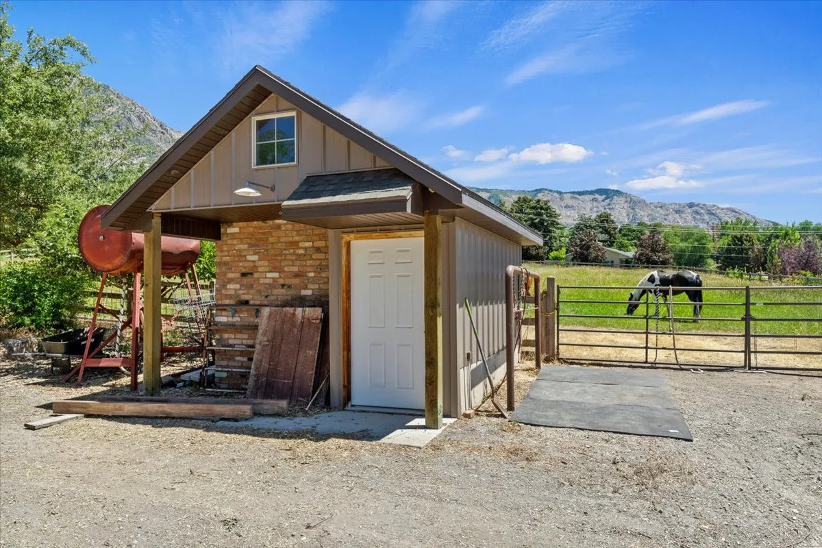 Tack shed featuring vertical siding and brick accents, an upper-level window, and covered entry