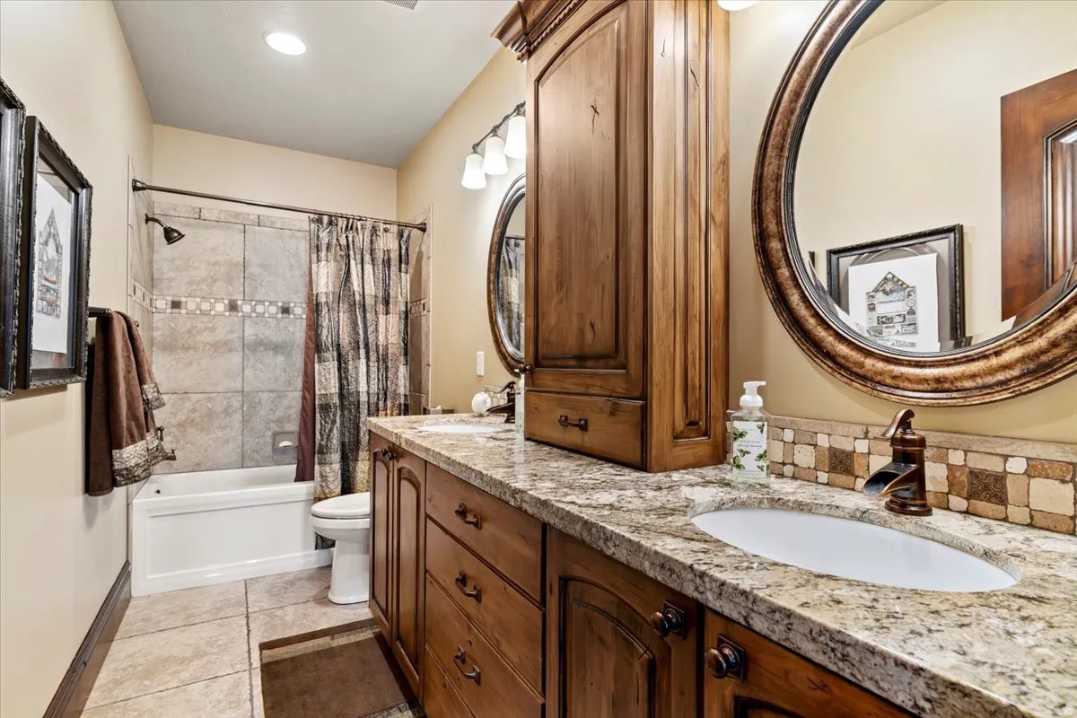 Bathroom featuring a dual vanity with wood cabinetry, granite-finish countertops, and under-mount sinks