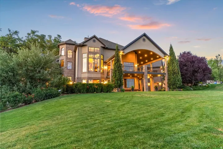 Expansive rear facade featuring multiple levels, extensive window arrangements, and a covered patio with integrated lighting
