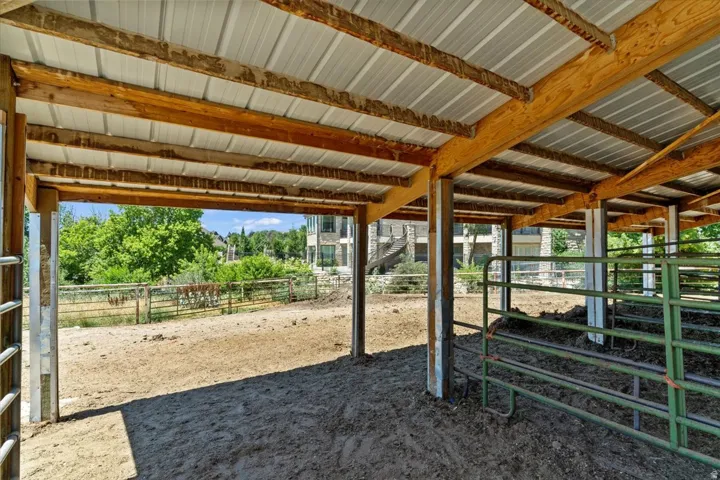 Open-air barn structure featuring a corrugated metal roof and exposed wood beams
