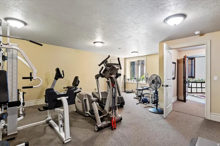Large dedicated fitness space featuring neutral wall tones and recessed lighting
