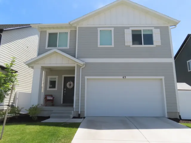 Two-story residence featuring light gray siding, white trim, a covered porch entry, an attached garage, and a concrete driveway