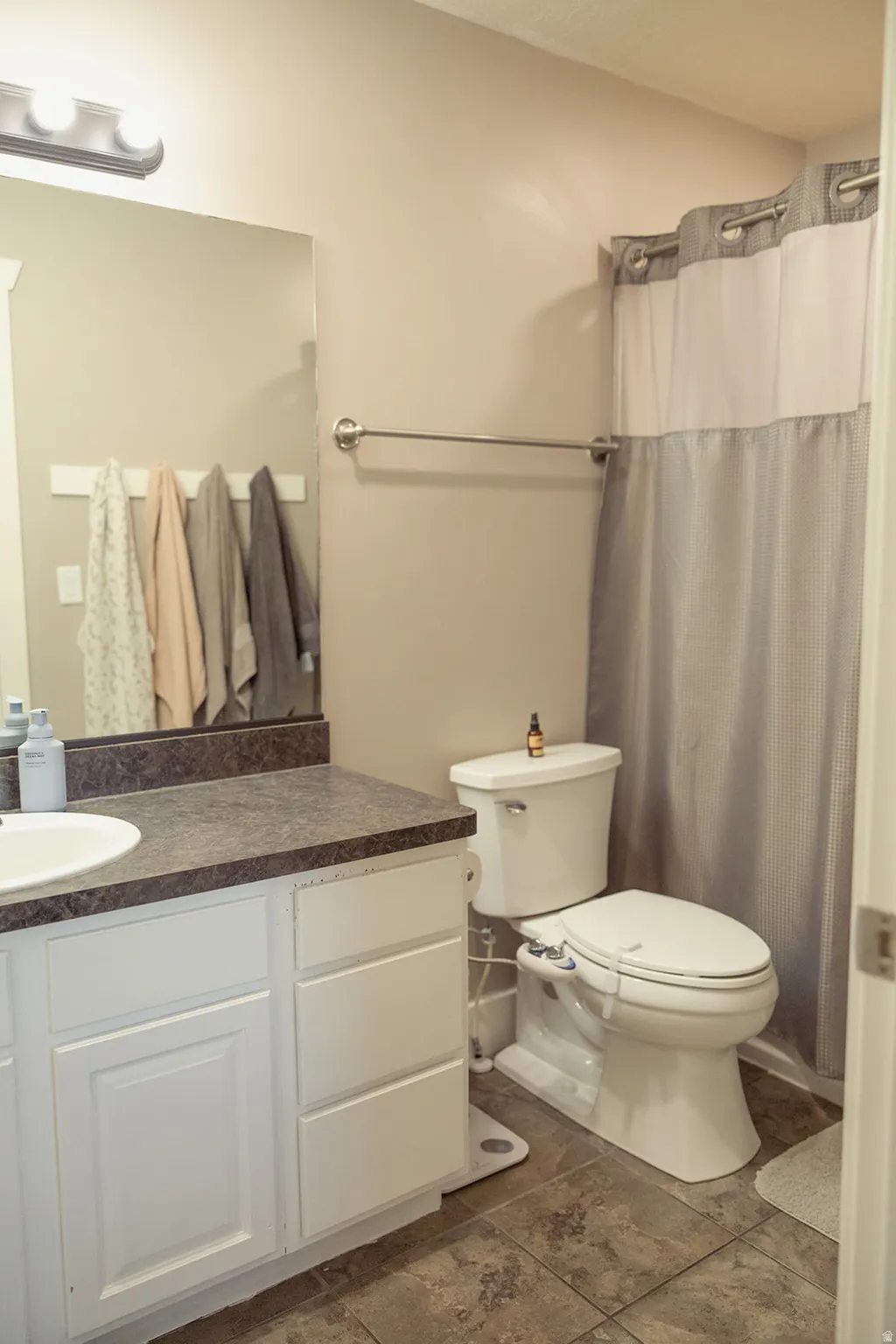 Bathroom vanity with white cabinetry, a dark speckled countertop, and an integrated white sink