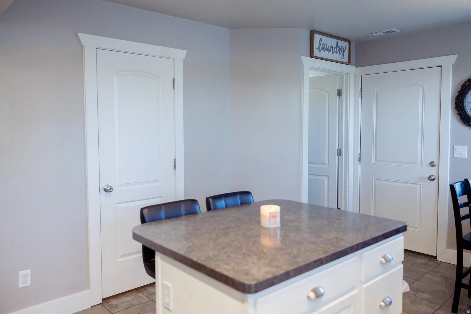 Kitchen island with a dark stone-look countertop and white cabinetry