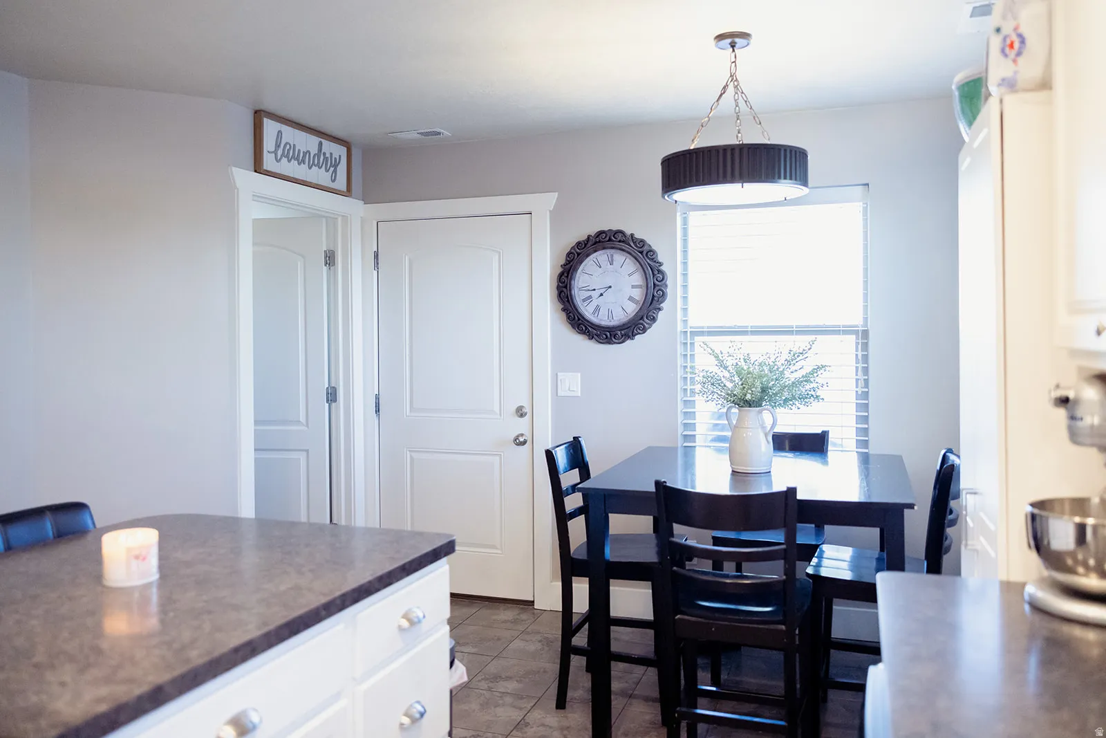Open concept kitchen and dining area featuring a window with blinds, a dark wood-finish dining table, and a contemporary drum pendant light fixture