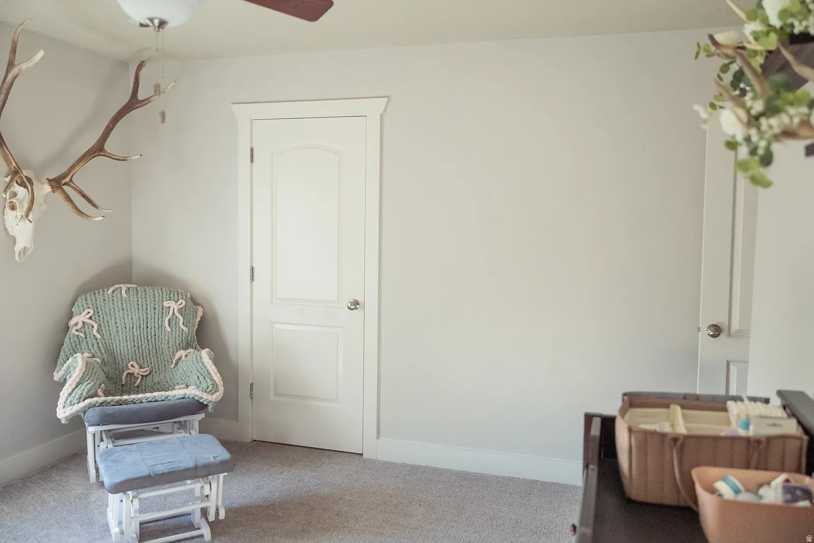 Carpeted room featuring light neutral wall paint, white baseboards, and a white interior door with a silver-toned doorknob