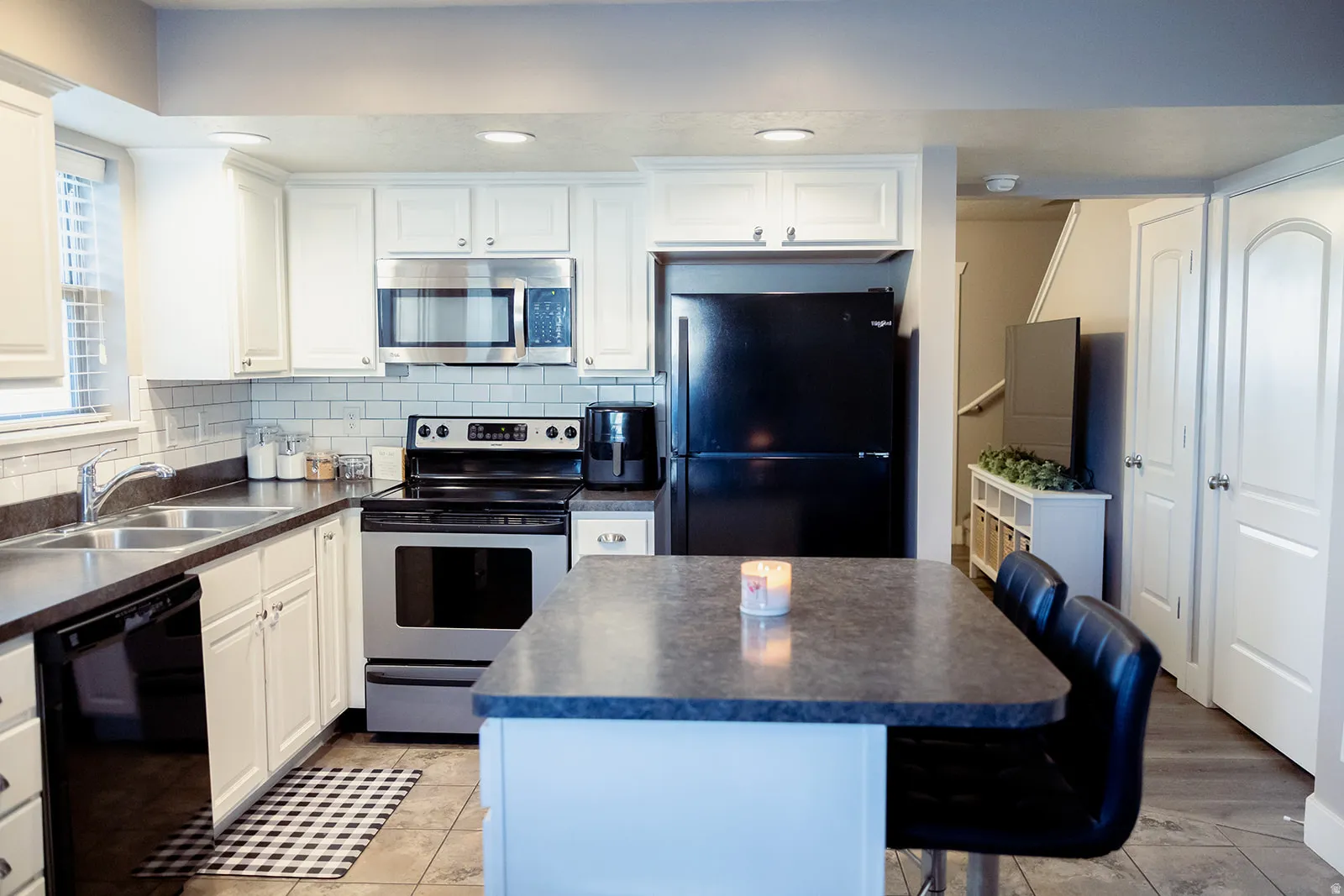 Kitchen featuring white cabinetry, subway tile backsplash, stainless steel appliances, and an island with seating
