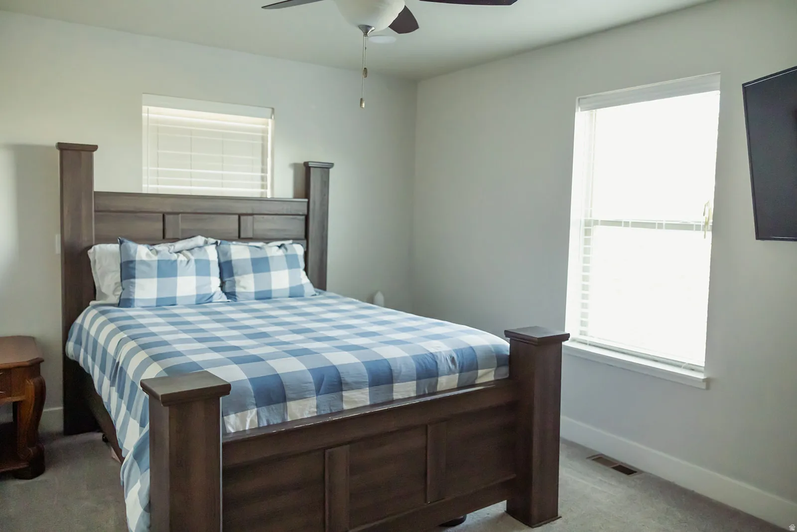 Carpeted bedroom featuring neutral wall tones, a ceiling fan, and a window with blinds