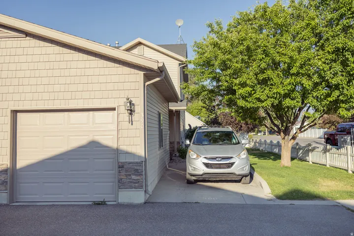 Exterior featuring shake siding, a single-car garage, stone veneer accents, and a mature tree