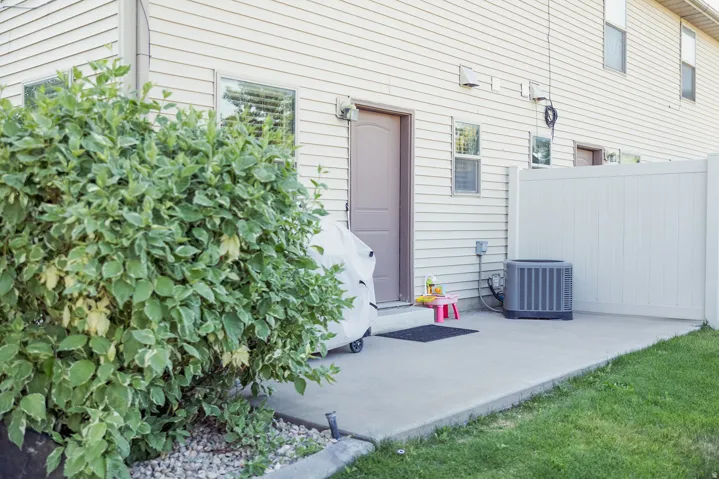 Concrete patio with white privacy fencing and a large air conditioning unit